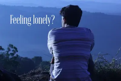 man sitting and looking on blue mountain background with text "feeling Lonely?"