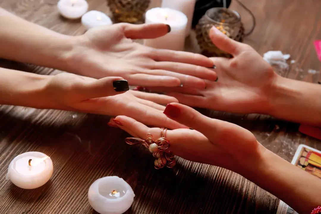 Two sets of hands facing up with white candles around them