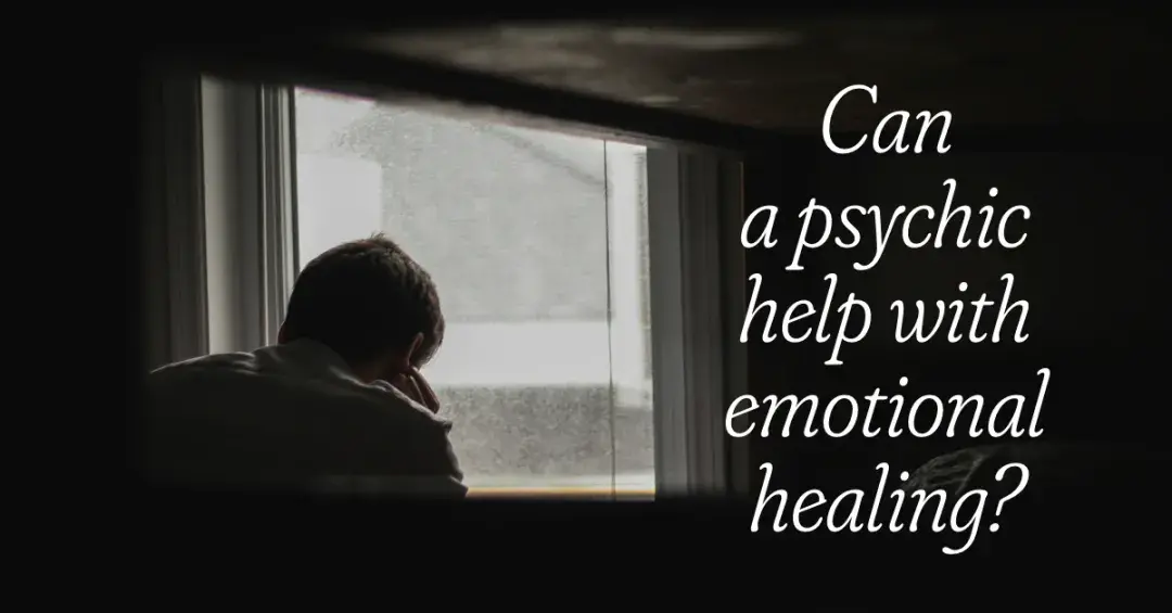 Person holding knee in front of window in dark room text "Can a Psychic help with Emotional healing?"