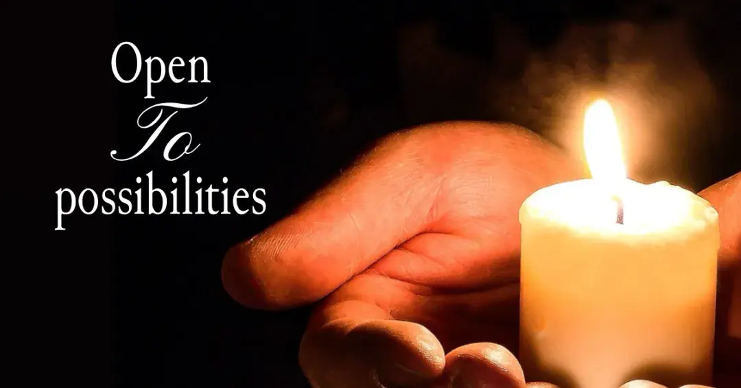white candle in hand with text "open to possibilities"