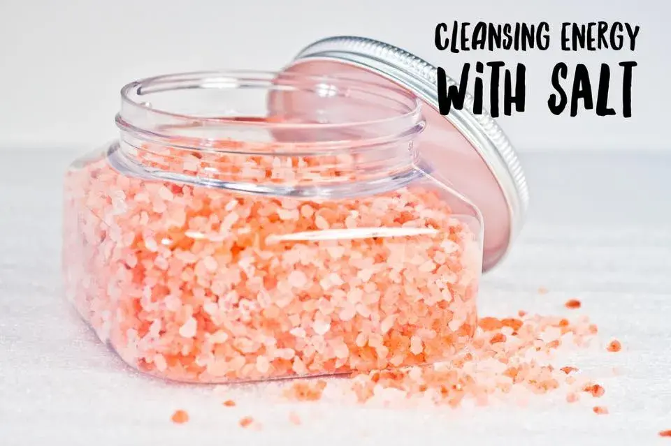 pink salt in glass jar with lid resting on the side Text "cleansing with salt"