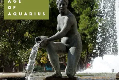 Aquarius statue with water, Age of Aquarius written in green box