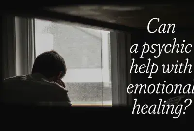 Person holding knee in front of window in dark room text "Can a Psychic help with Emotional healing?"
