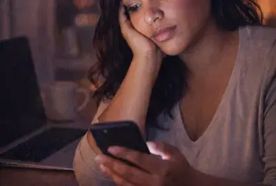 woman checking her phone wondering why her ex keeps checking her social media but never reaches out