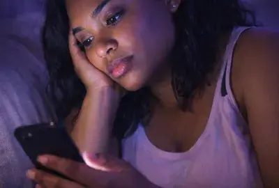 Woman looking at her phone at night wondering why her ex likes her social media posts but never texts her